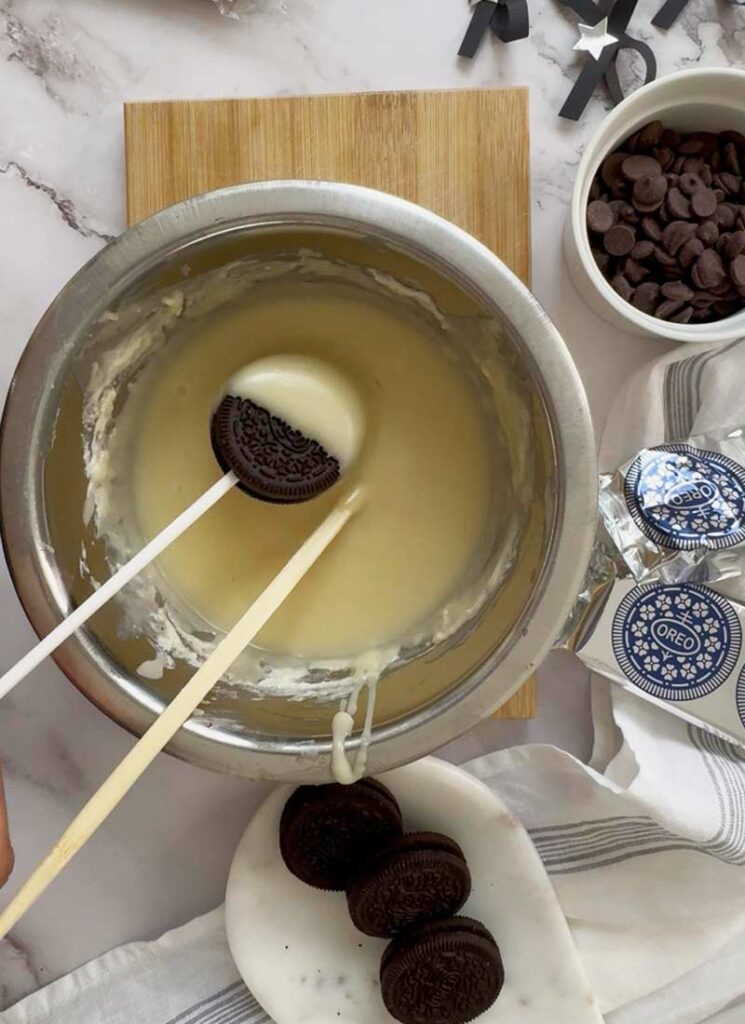 Dipping Oreos on a stick into creamy white chocolate coating.